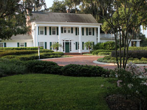 Historic white estate house and landscaped lawn. No dog area visible.