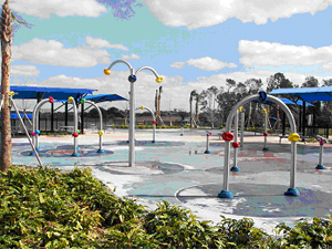 Splash pad with shade canopies. No dog area visible; source appears posterized.