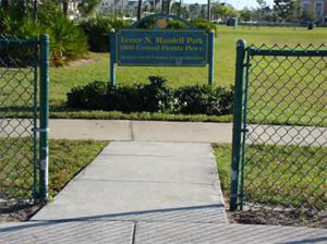 Park entrance gate, sign, and open field. No dogs visible.
